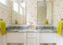 Pink girl's bathroom features a white dual washstand topped with dark gray marble fitted with two sinks placed under polished nickel mirrors and 2-light downlight sconces.