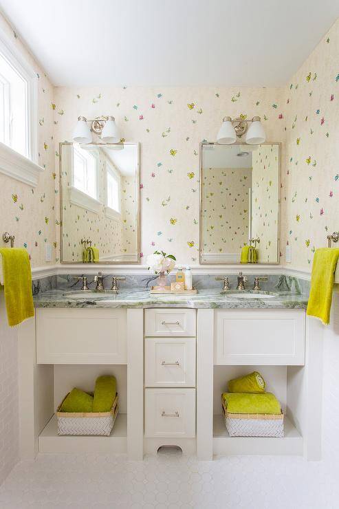 Pink girl's bathroom with white cabinets, dark gray marble fitted with two sinks placed under polished nickel mirrors 