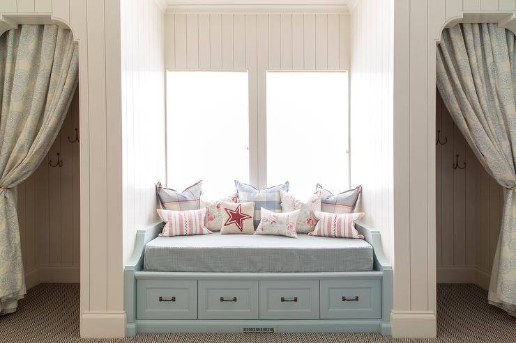 Blue built in reading nook with a window seat bench and storage drawers underneath in a girls bedroom design.