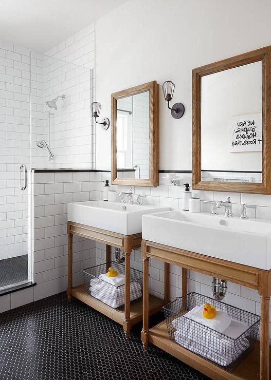 weathered oak vanity mirror mounted on white walls accented with white subway backsplash tiles placed on black hex floor tiles 