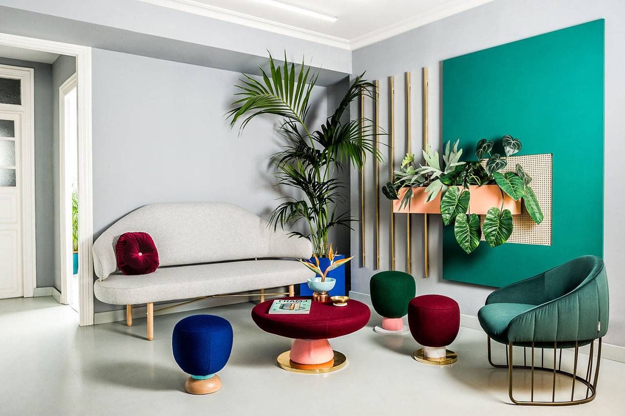 living room with colorful geometric seats, turquoise colorblock wall and large foliage