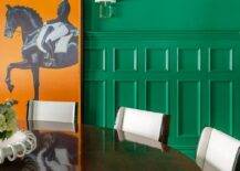 Hermes orange art hangs from a green wainscot dining room wall.