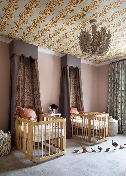 Nursery features dual gold oak cribs with orange and taupe scalloped valance and curtains, green animal print curtains and orange ceilng wallpaper.