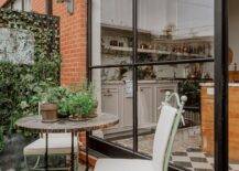 Mint green wrought iron chairs with white cushions are placed on a French style balconette at a marble bistro table.