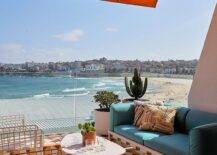 Balcony features orange and yellow mosaic floor tiles, a marble top coffee table and a turquoise blue sofa under an orange awning.