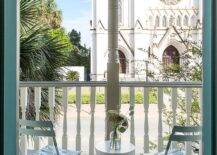 Chic balcony is filled with blue slatted folding chairs and a white hourglass accent table.