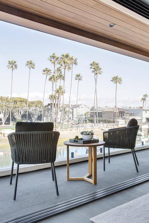 Bedroom balcony boasts modern black rope chairs and a round wooden accent table.