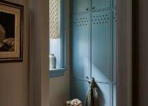 Terracotta floor tiles lead to floor-to-ceiling blue mudroom cabinets with oil rubbed bronze knobs.
