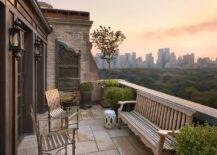 Chic balcony features a teak bench facing a pair of wrought iron chairs.