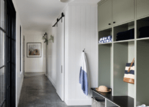 Mudroom features green lockers with woven baskets on a concrete floor.