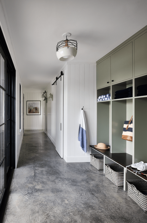 Mudroom features green lockers with woven baskets on a concrete floor.