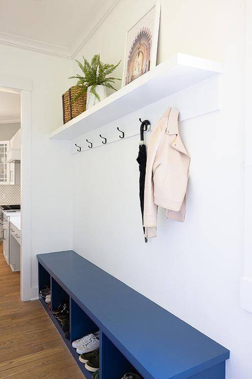 Mudroom features a blue bench with cubbies under a row of hooks on a white shelf.