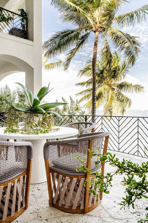 Covered patio features gray wicker and rope dining chairs at a white pedestal table.