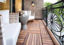 Small transitional balcony made of iron and teak displaying modern wicker club chairs. A concrete accent table is flanked by white upholstered chairs creating stunning patio design.