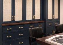 Den features blue cabinetry with cane doors and brass pulls and a blue desk with black chairs.