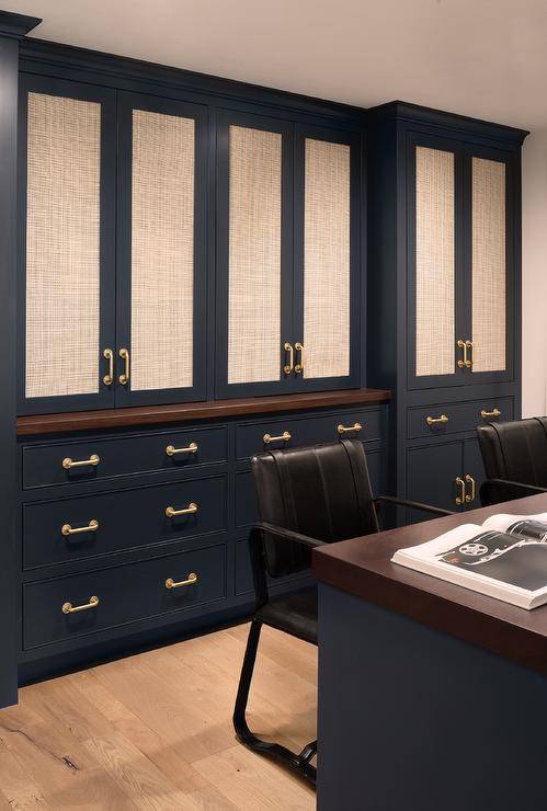 Den features blue cabinetry with cane doors and brass pulls and a blue desk with black chairs.