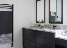 Modern black and white bathroom features a black dual washstand topped with black and white marble and a matte black gooseneck faucet under black framed inset medicine cabinets and black geometric floor tiles.
