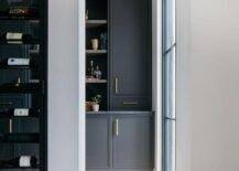 Pantry features black cabinets accented with brass pulls and black marble countertop.