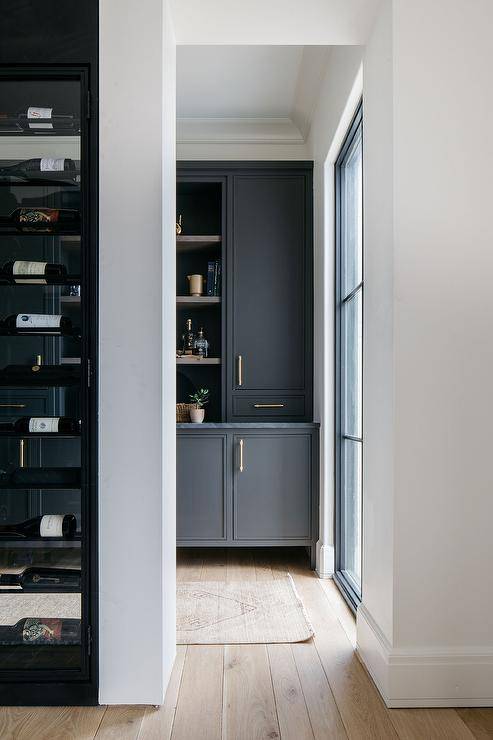 Pantry features black cabinets accented with brass pulls and black marble countertop.