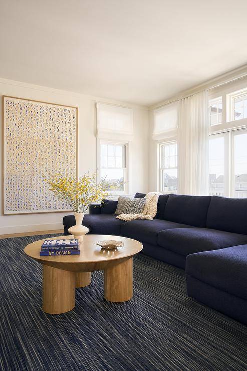 Living room features a blueberry blue sectional on an ivory and blue rug with a vintage round oak coffee table.