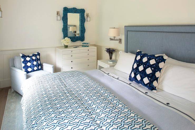 Bedroom features a blue coral mirror over a tall white dresser, a blue headboard with blue trellis pillows and a light blue accent chair.