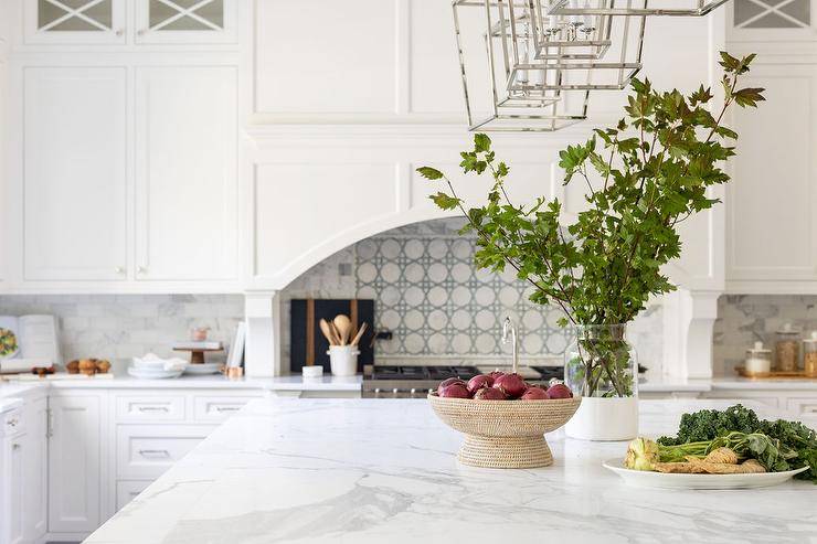Darlana Lanterns light a white and gray quartz kitchen island countertop styled with a woven pedestal bowl.
