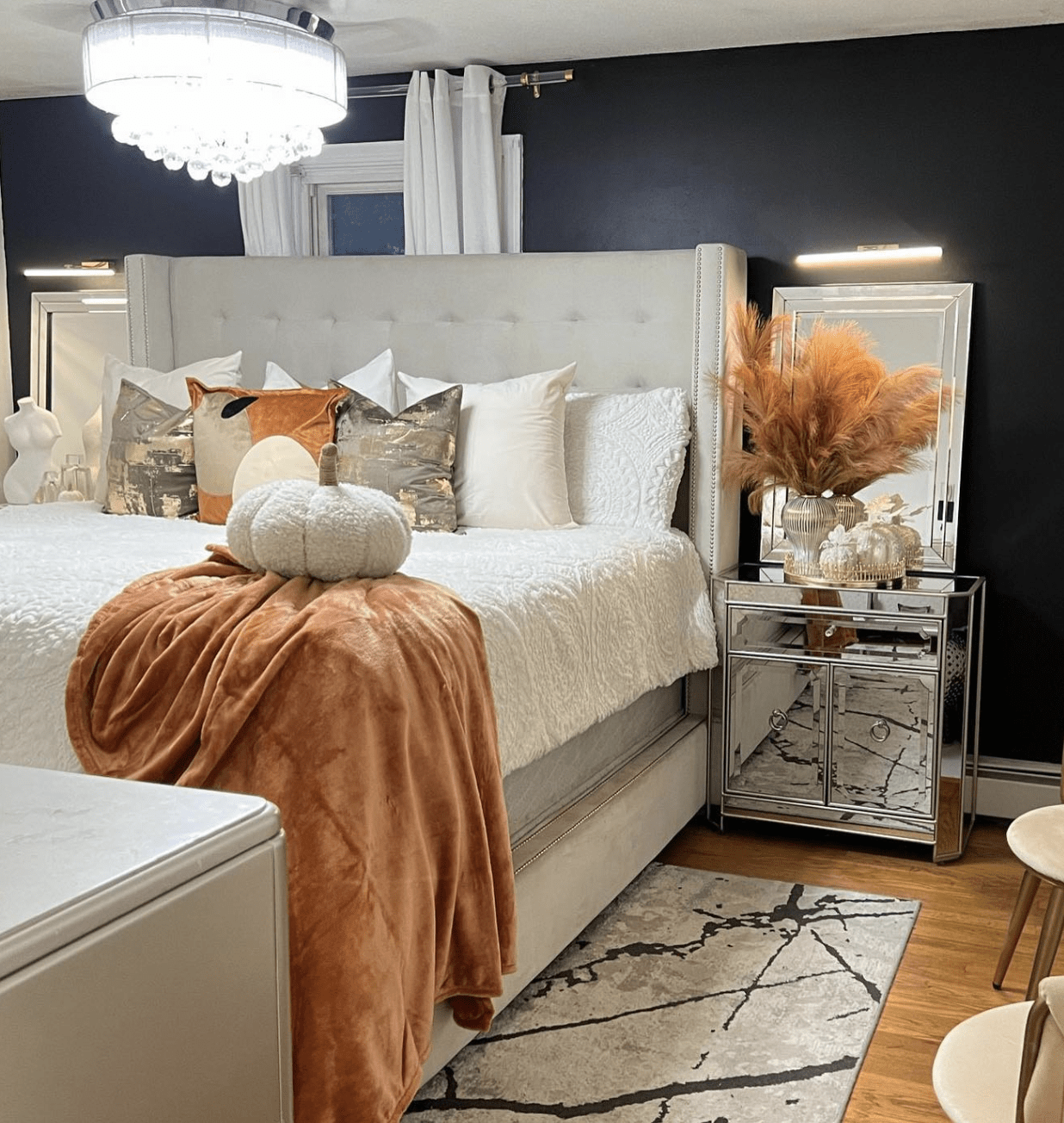 fall theme color palette bedroom with tufted headboard, navy walls and mirrored nightstand