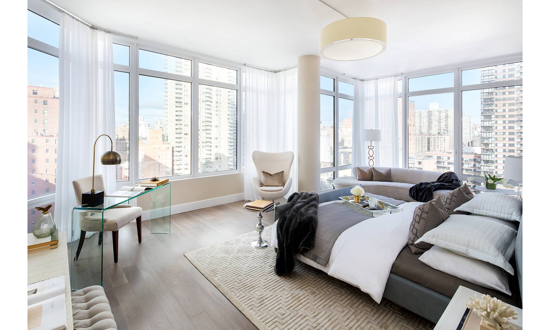 Spacious bedroom with floor-to-ceiling windows on the sides of the room and a partial floor-to-ceiling window in the middle.