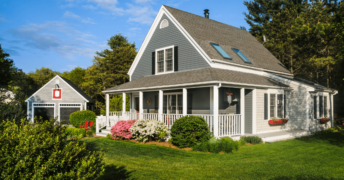 Cape Cod house flanked by detached double door garage.