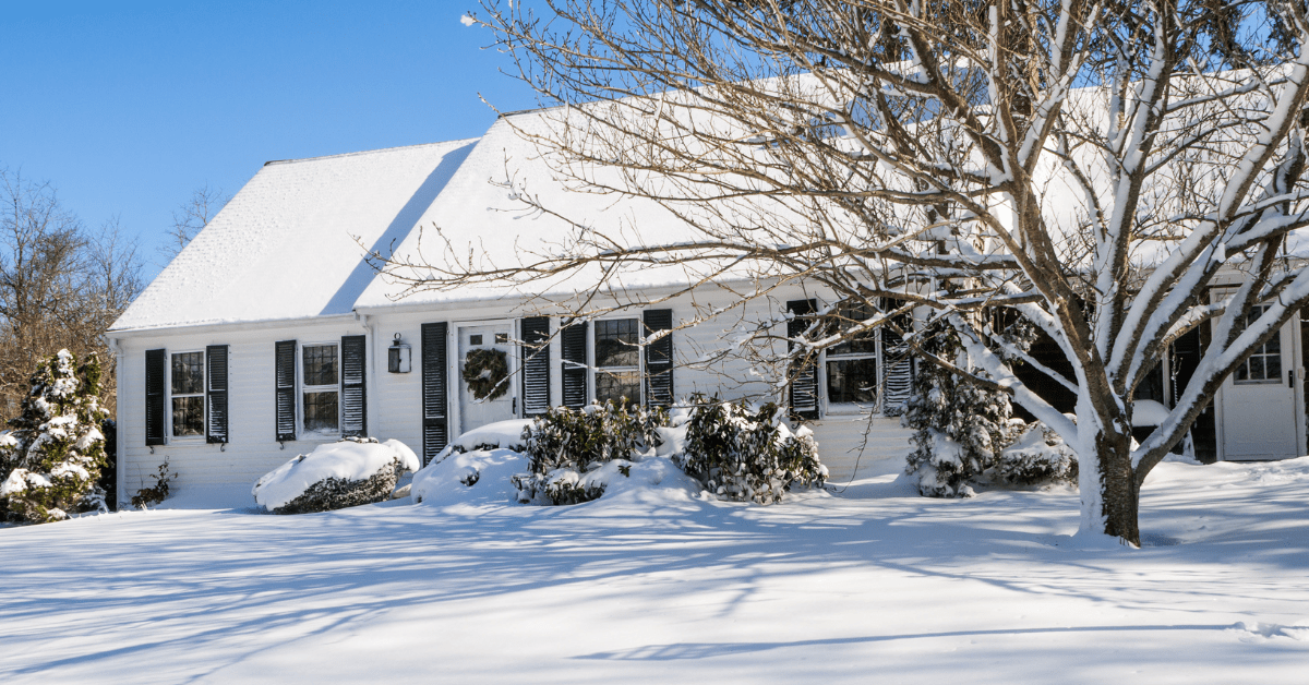 Cape Cod styled house in winter, covered in snow.