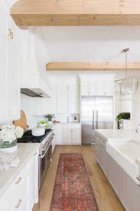 Crisp and clean kitchen in the Hilltop Home. Nickel lighting fixture with marble countertops, and white cabinets. Colorful vintage runner that adds personality to the space.