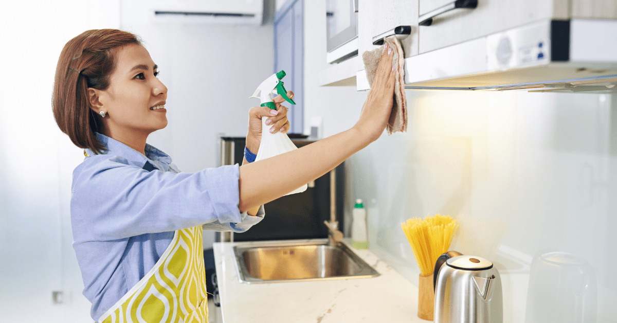 Person using a cloth and spray to clean and maintain kitchen cabinets.