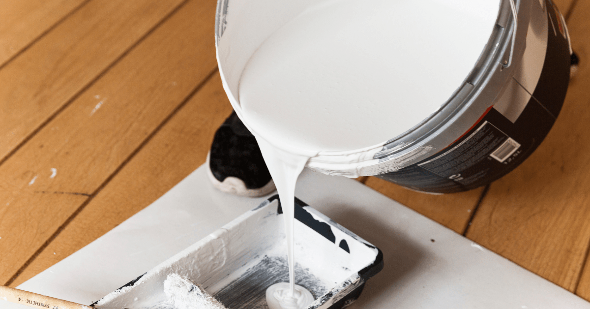 Pouring primer from a bucket into a roller pan.