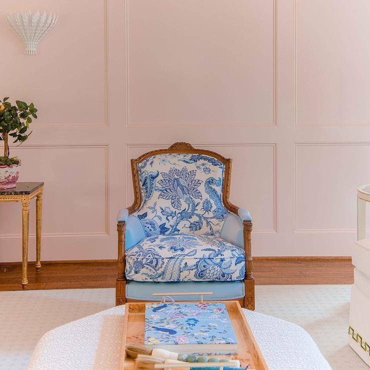 A gold french chair is finished with blue chinoiserie fabric and placed in front of a wainscot wall.
