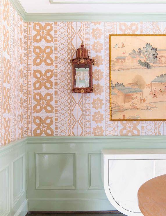 Dining space features orange batik wallpaper over mint green wainscoting.