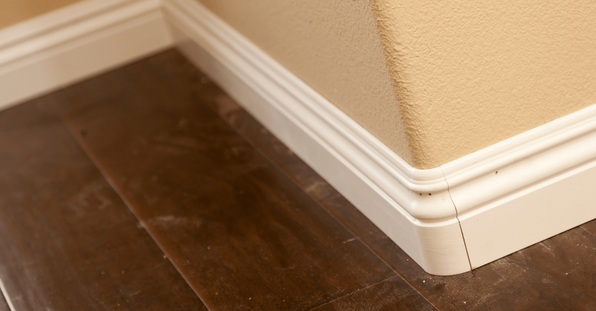 Dirty floors around white baseboards.