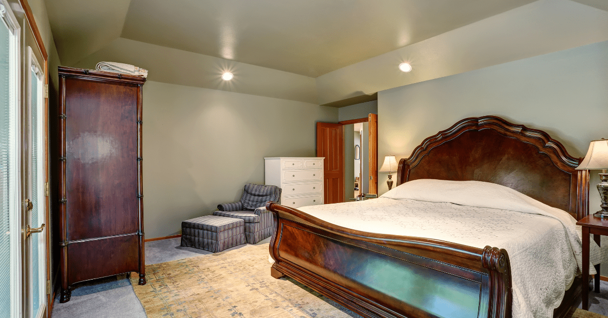 Wood frame king size bed in bedroom, which has a rug underneath.