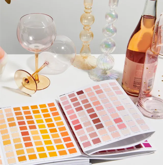 Wine and glasses on a table with an open Peach Fuzz 13-1023 color palette.