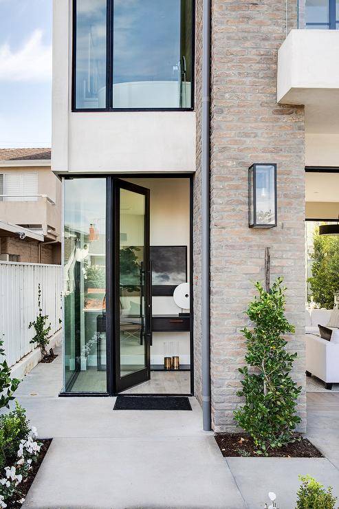 Modern brick beach home features glass windows, modular accents and lush green plants for a natural green finish.