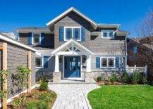 Craftsman style home features gray shingles, a blue front door, blue shutters and a stone paver walkway.