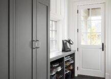 Charcoal gray chevron pattern floor tiles in a gray mudroom completed with gray built in cabinets and a gray bench. White plank walls contrast the gray hues in the mudroom bringing a perfectly balance of hues and interest. Stacked shoe shelves at the entry adds extra organizational appeal to the overall mudroom design.