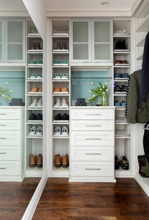 Custom walk-in closet features gray faux boi wallpaper behind built-in shoe shelves flanking stacked drawers and frosted cabinets.