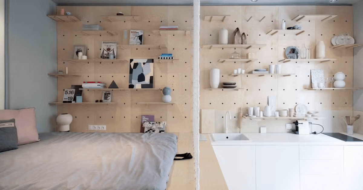 Studio apartment with pegboard and shelves storage on wall.
