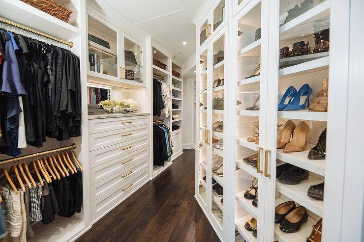 Custom walk-in closet featuring glass shoe cabinets with interior cabinet lighting for a couture-like appeal.