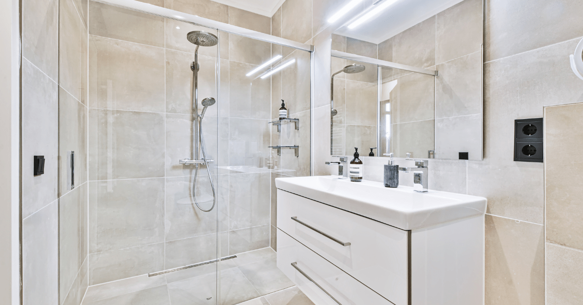Banheiro branco com louças em inox e chuveiro.