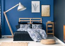 indigo wall in bedroom with wooden bedframe and rattan decor
