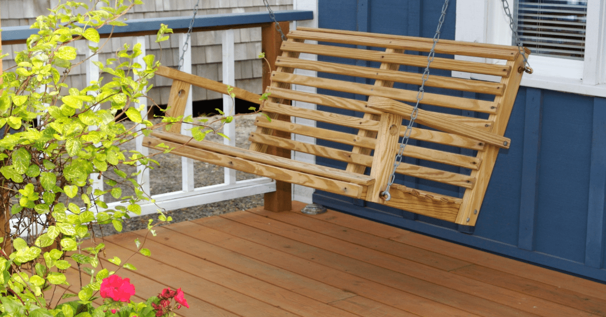 Uma varanda com balanço e deck de madeira.