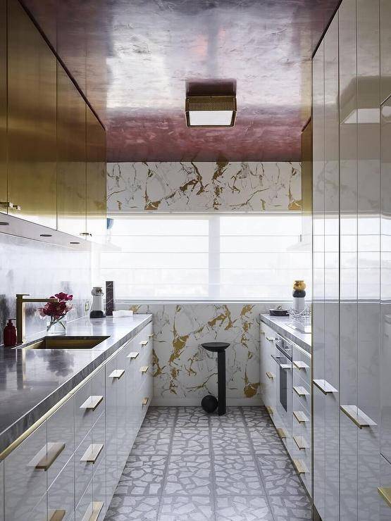 Contemporary kitchen features white and gold lacquer cabinets with black marble top and a red ceiling.
