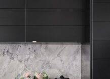 Modern gray and black kitchen features black plank cabinets with a gray marble slab backsplash.