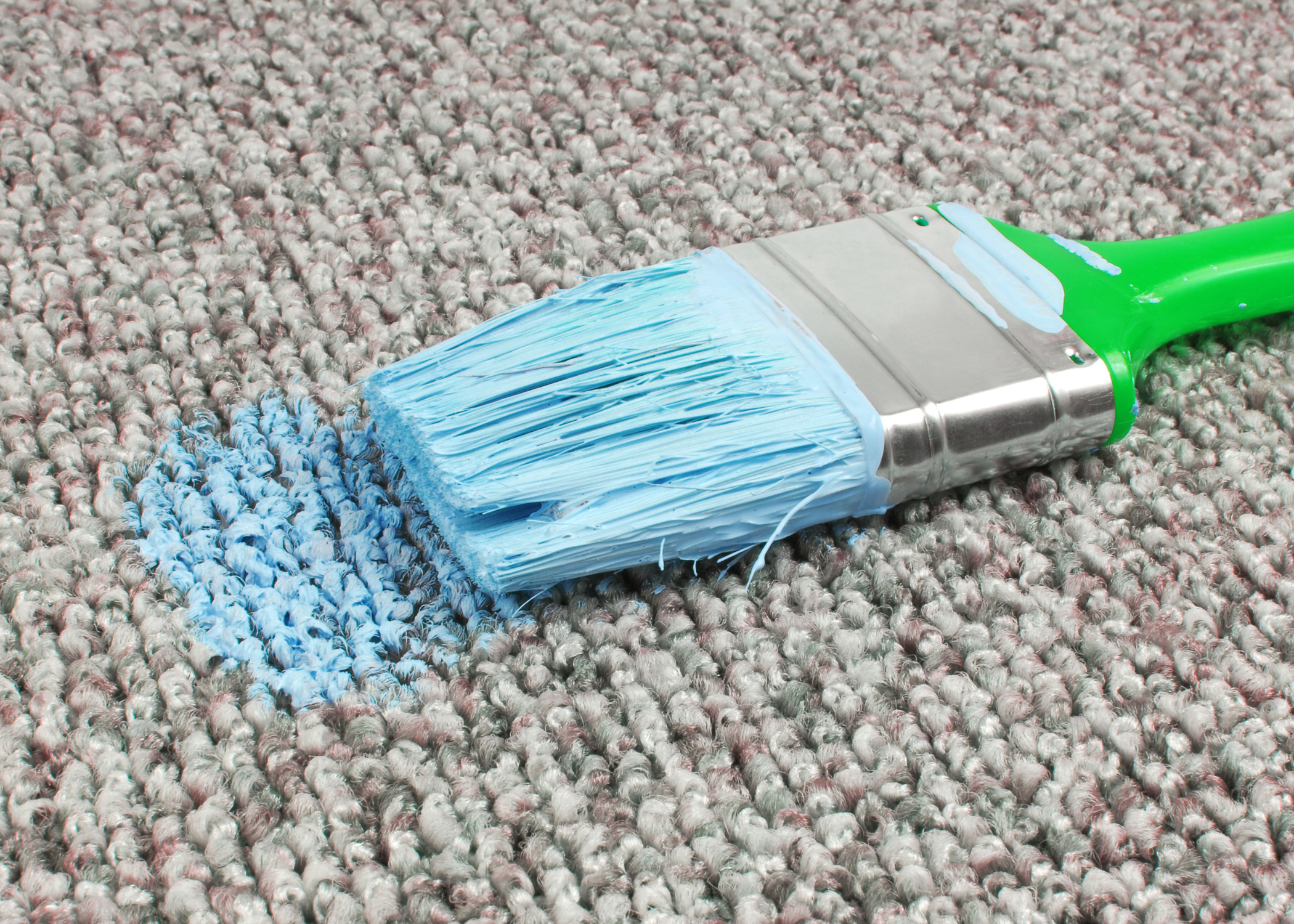 paint brush on a carpet with blue paint